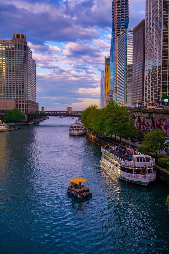 Elegant view of the Chicago River lined with modern skyscrapers and vibrant boats during sunset.